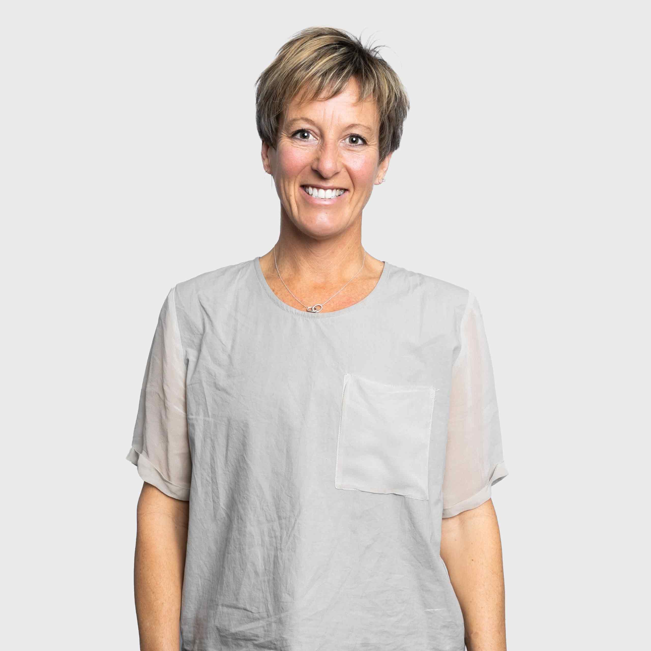 Emily Higgins is a Caucasian woman with short brunette hair. She is smiling and is wearing a grey top.